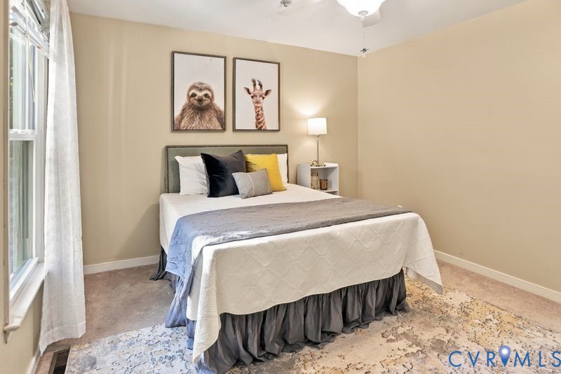 Neutral-toned interior space featuring carpeted flooring, large window with natural light, and a ceiling-mounted light fixture