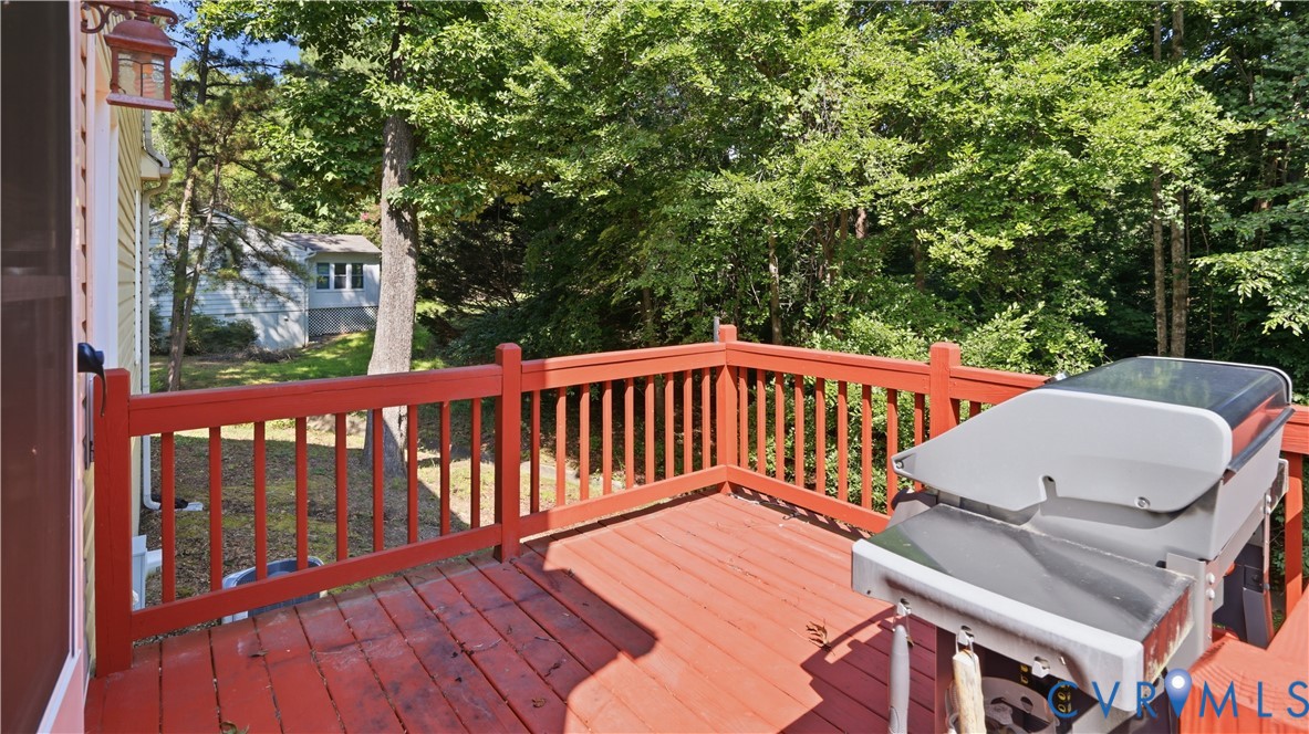 Raised outdoor deck featuring painted wood decking, matching picket railings, and an attached exterior wall-mounted light fixture