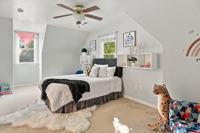 Bedroom featuring angled ceilings, carpeted flooring, wall-mounted white cubby shelving, and a brass-finish ceiling fan with integrated lighting