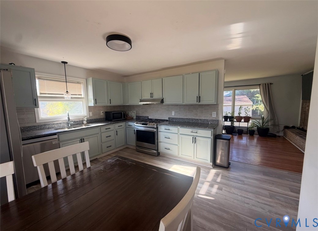Kitchen featuring light-toned cabinetry, stone-finish countertops, stainless steel appliances, a tile backsplash, and recessed ceiling lighting