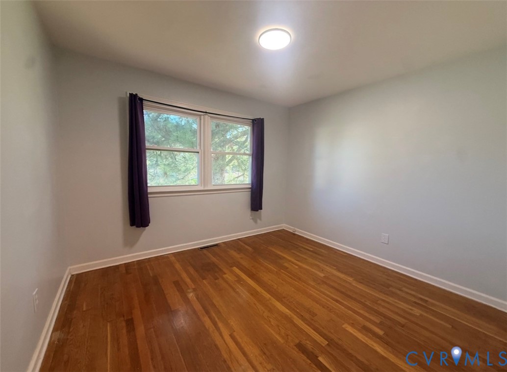 Room featuring wood-finish flooring, double-pane windows, and a flush-mount ceiling light fixture