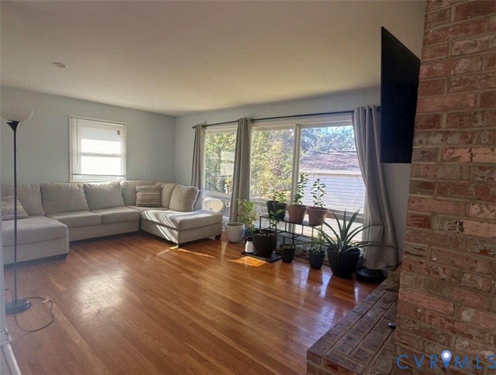 Wood-finish flooring, floor-to-ceiling multi-panel windows, and exposed red brick chimney feature
