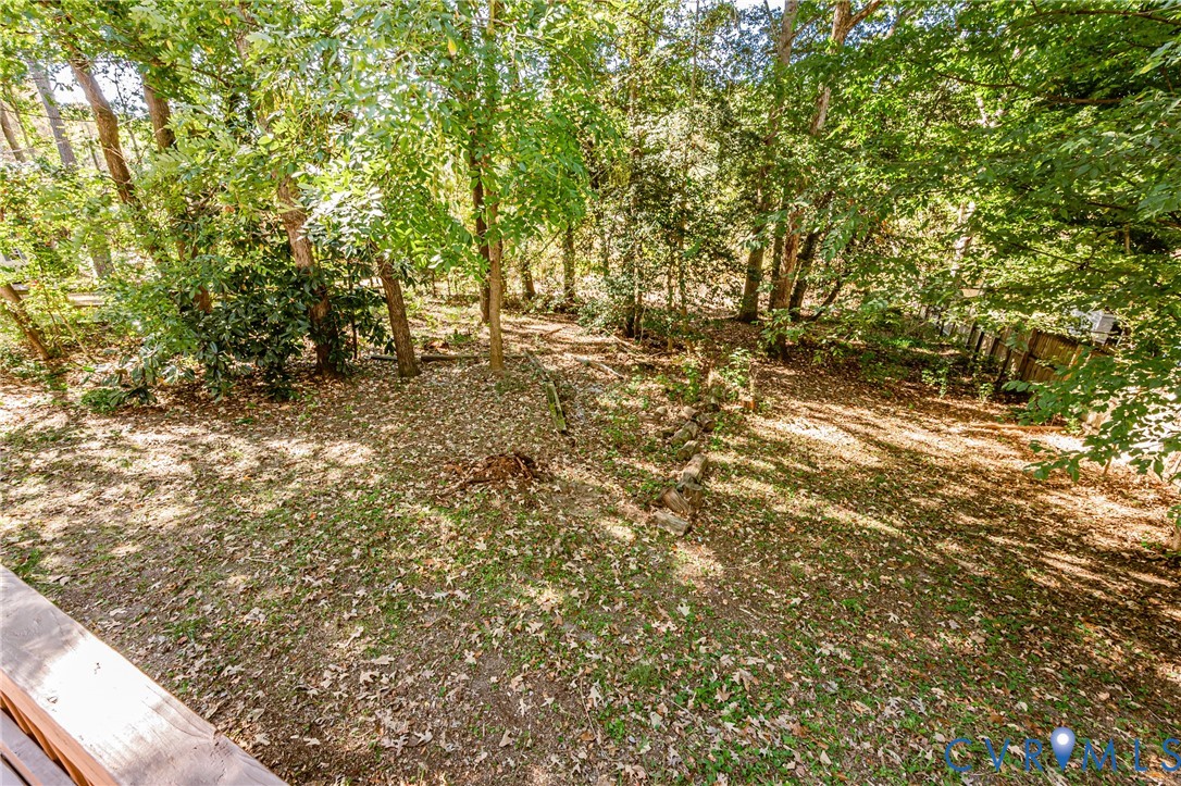 Spacious backyard featuring mature trees, natural landscape, and a tiered stone retaining wall