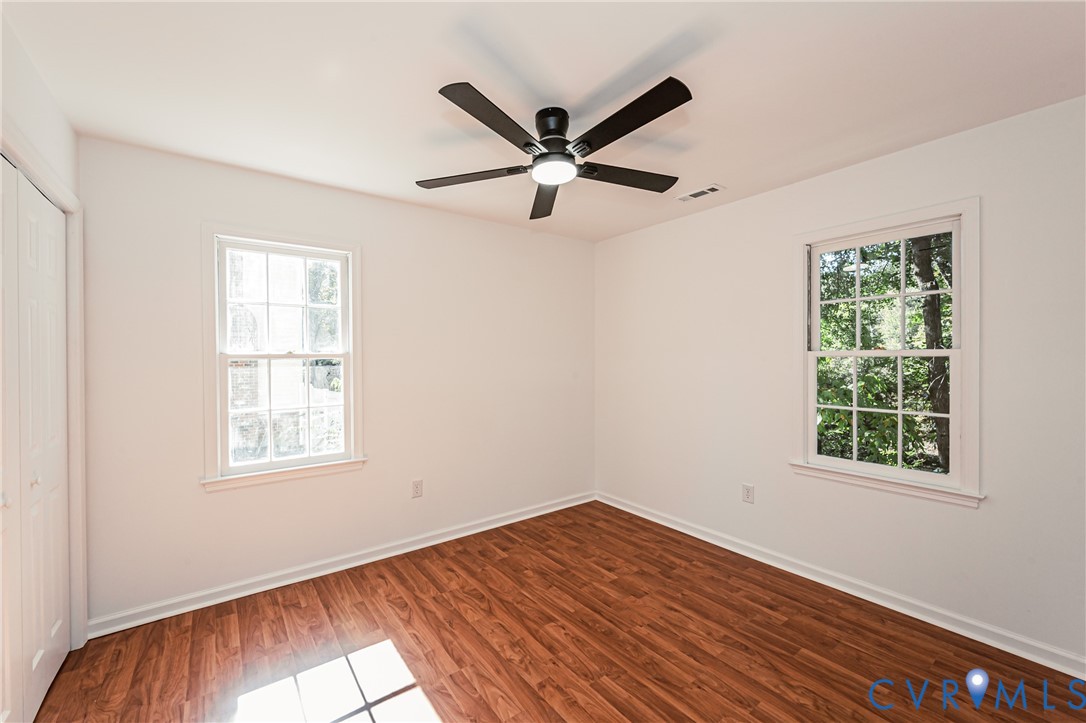 Interior space featuring wood-finish flooring, two double-hung windows with muntin detailing, and a central ceiling fan with integrated lighting