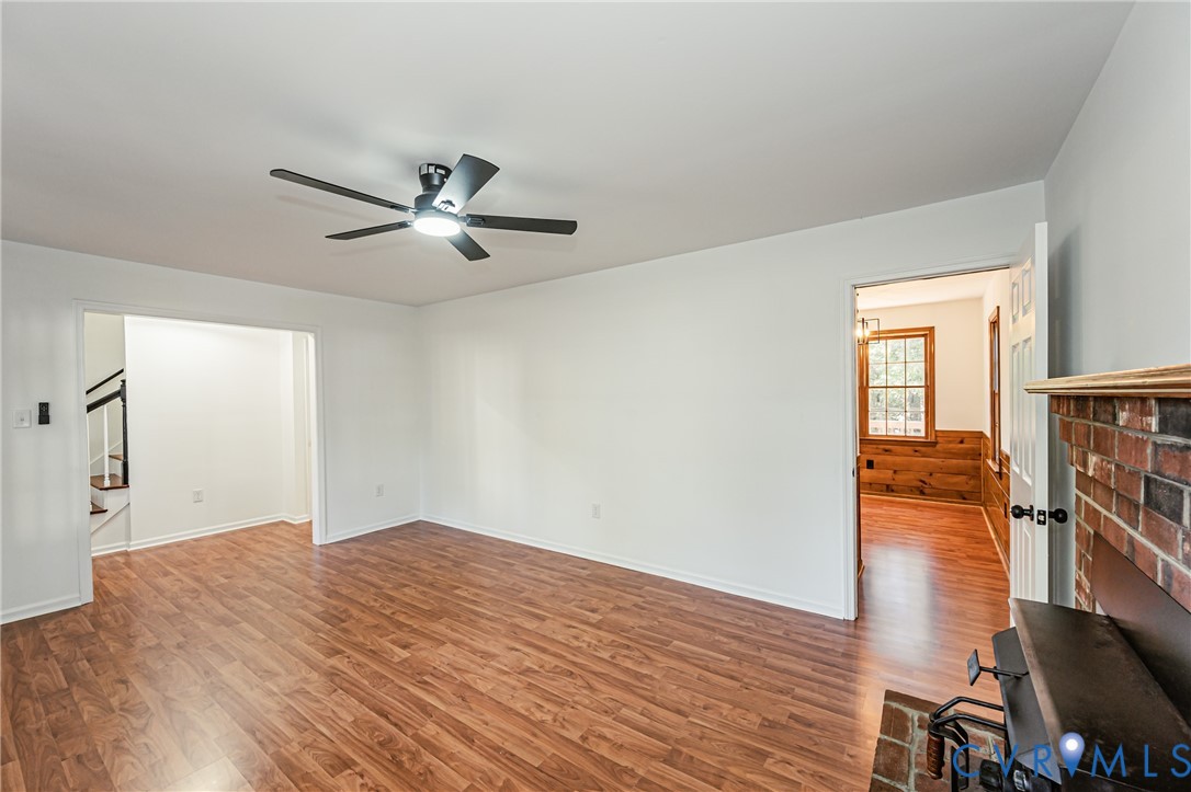 Interior space featuring wood-finish flooring, a ceiling fan with integrated lighting, and a brick fireplace hearth