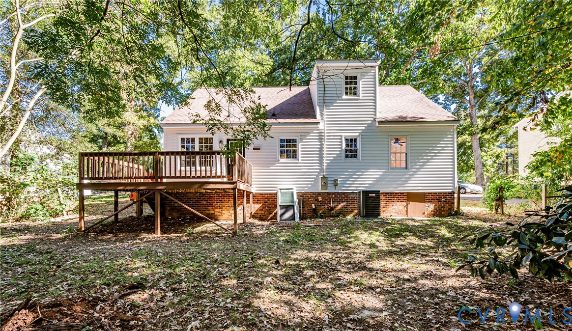 Exterior siding featuring a multi-level structure with a brick foundation, elevated wood deck, and mature surrounding trees