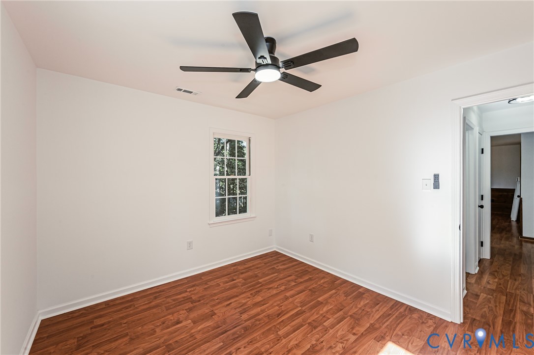 Room featuring wood-finish flooring, a multi-blade ceiling fan with integrated lighting, and a single-pane window with grid muntins