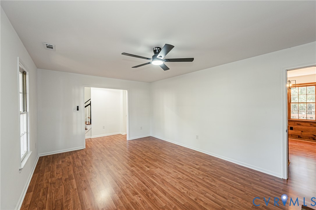 Interior space featuring wood-finish flooring, white walls, and a ceiling-mounted fan with integrated light fixture