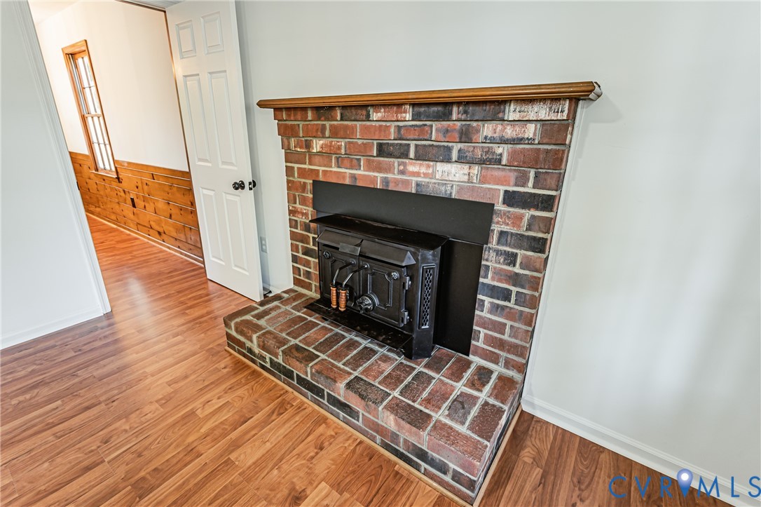 Multicolor brick fireplace featuring a wood-burning stove insert, raised brick hearth, and wood-finish mantle