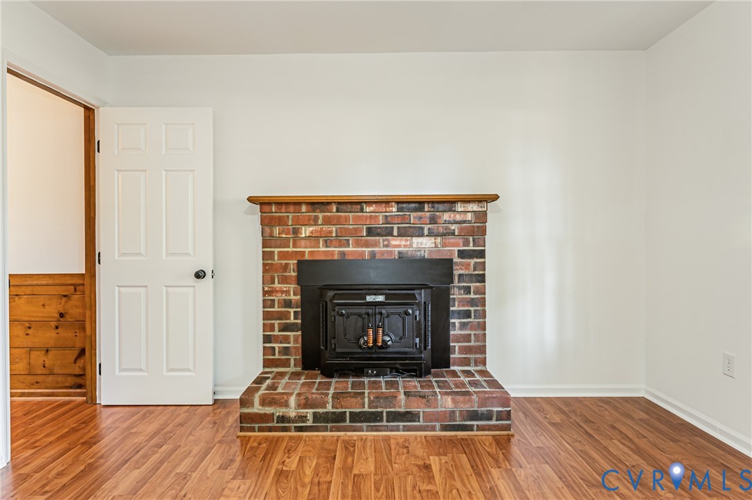 Multi-toned brick fireplace with a wood-finish mantel, integrated black metal stove insert, and wood-finish flooring