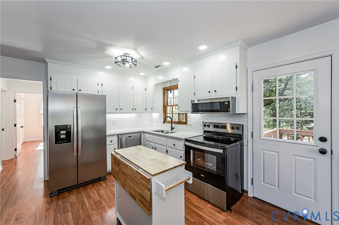 Kitchen featuring white cabinetry, wood-finish flooring, stainless steel appliances, white subway tile backsplash, and recessed lighting