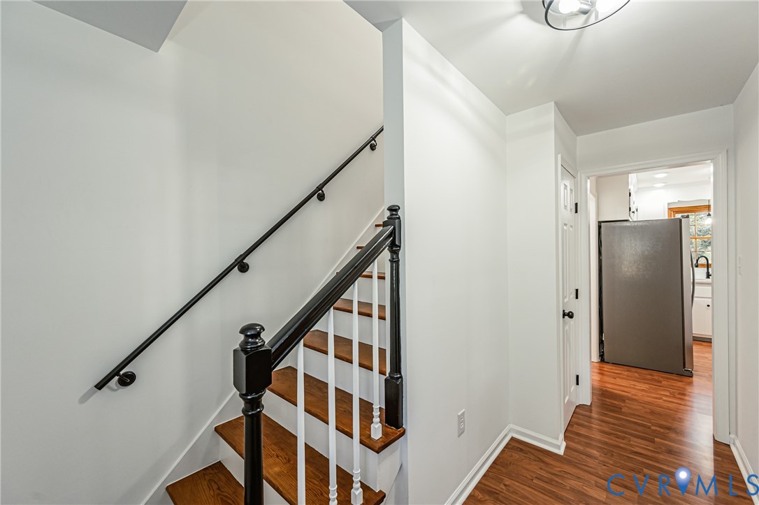 Staircase featuring wood-finish treads, white balusters, and a black-finish handrail