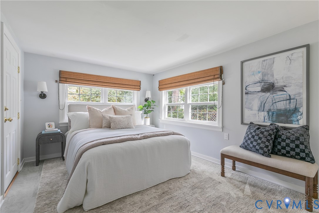 Neutral-toned interior featuring dual windows with woven wood shades and wall-mounted light fixtures