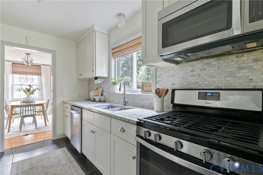 Kitchen featuring stainless steel appliances, shaker-style cabinetry, stone-finish countertops, and a tiled backsplash