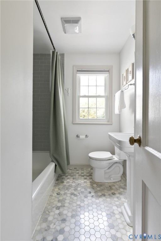 Full bathroom featuring hexagonal mosaic tile flooring, a pedestal sink, a bathtub with a tiled surround, and a double-hung window