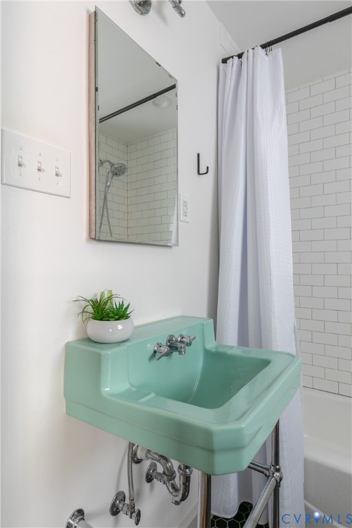 Wall-mounted mint-green porcelain pedestal sink with polished chrome hardware, rectangular mirror, and tub surround featuring white subway tile
