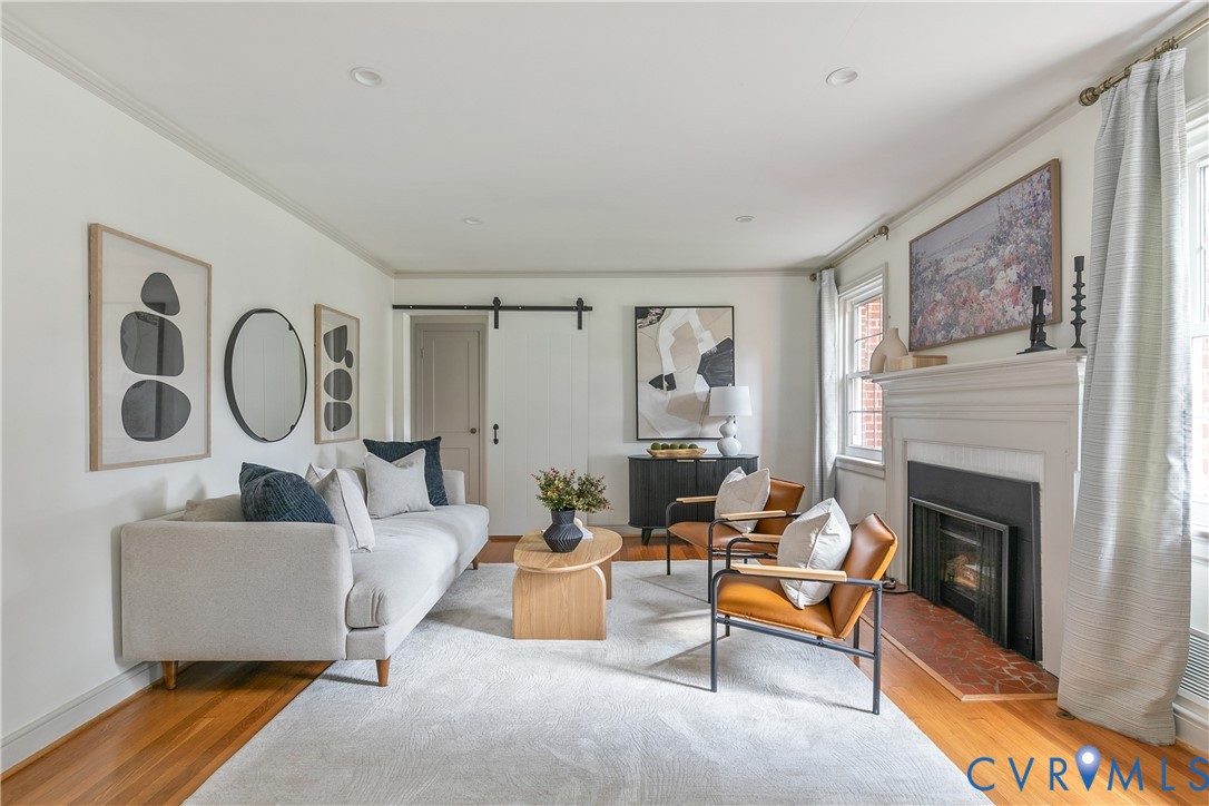 Living area featuring wood-finish flooring, a fireplace with a decorative mantel and terracotta-toned hearth, and a sliding door with black iron hardware