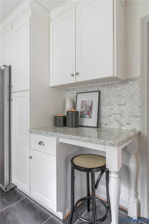 Built-in cabinetry featuring Shaker-style doors, stone countertop, decorative turned post leg, and mosaic tile backsplash