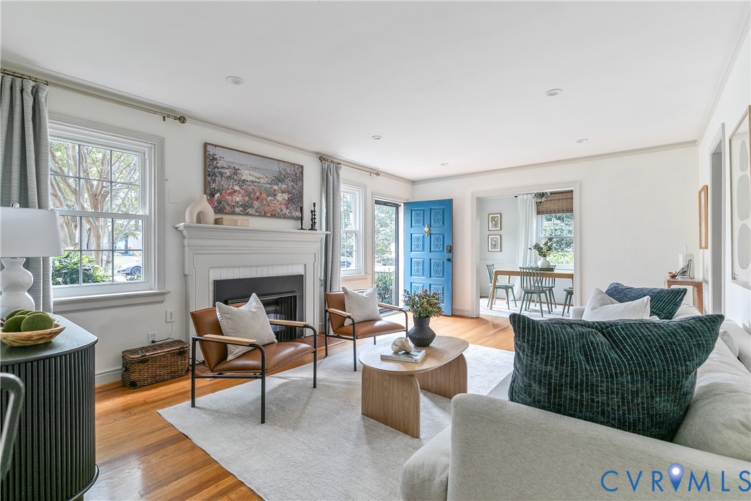 Living room featuring wood-finish flooring, a traditional fireplace with a white mantel, recessed lighting, and a paneled blue entry door