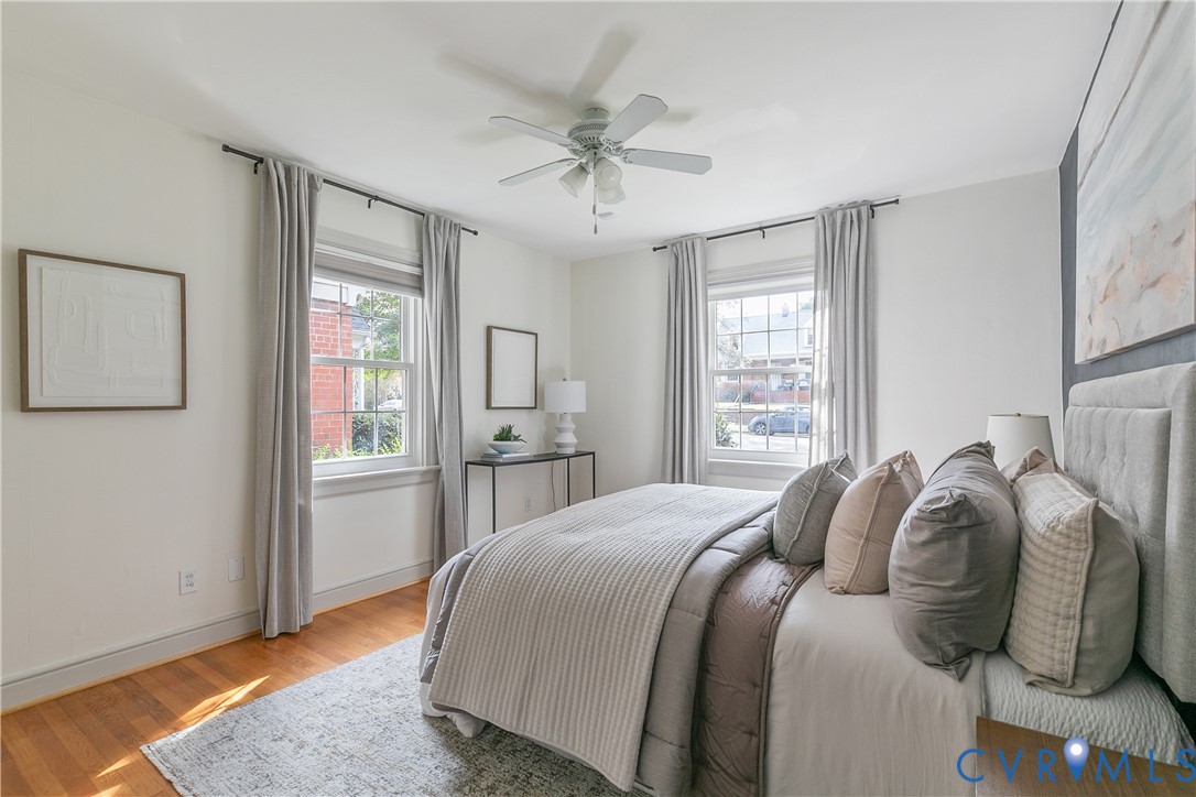 Bright room featuring wood-finish flooring, two double-hung windows, and a central ceiling fan with integrated lighting