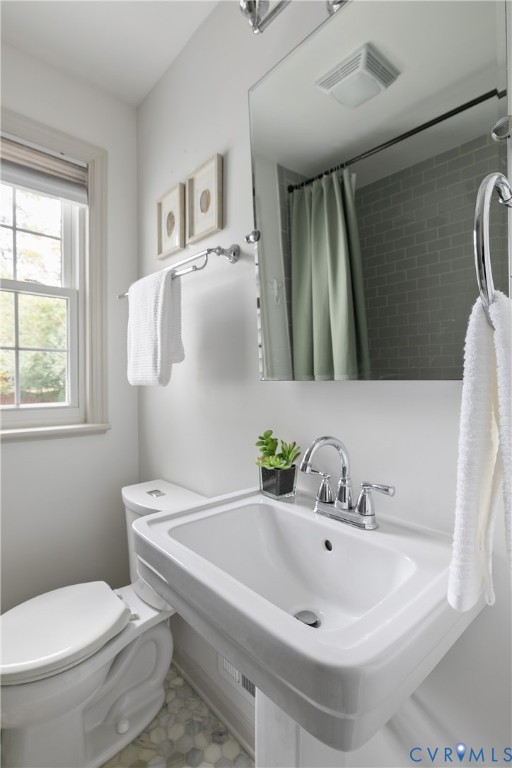 Wall-mounted pedestal sink with polished chrome widespread faucet, frameless mirror, hexagonal tile flooring, and subway tile shower surround