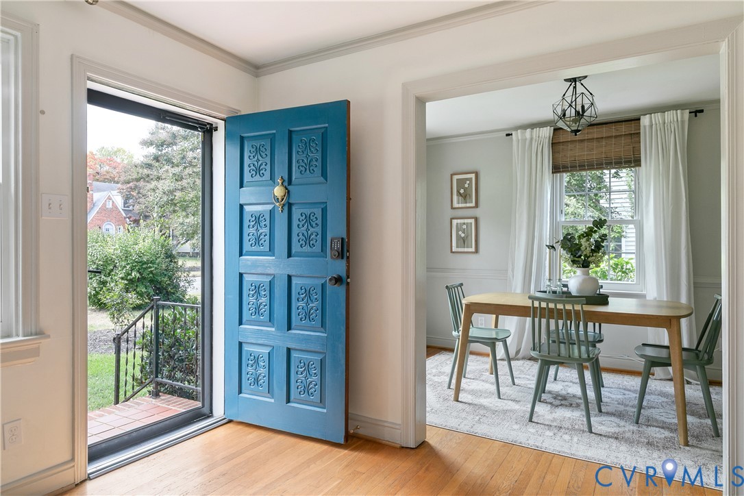 Entryway featuring a bold blue paneled door with a brass knocker, wood-finish flooring, and a geometric pendant light fixture