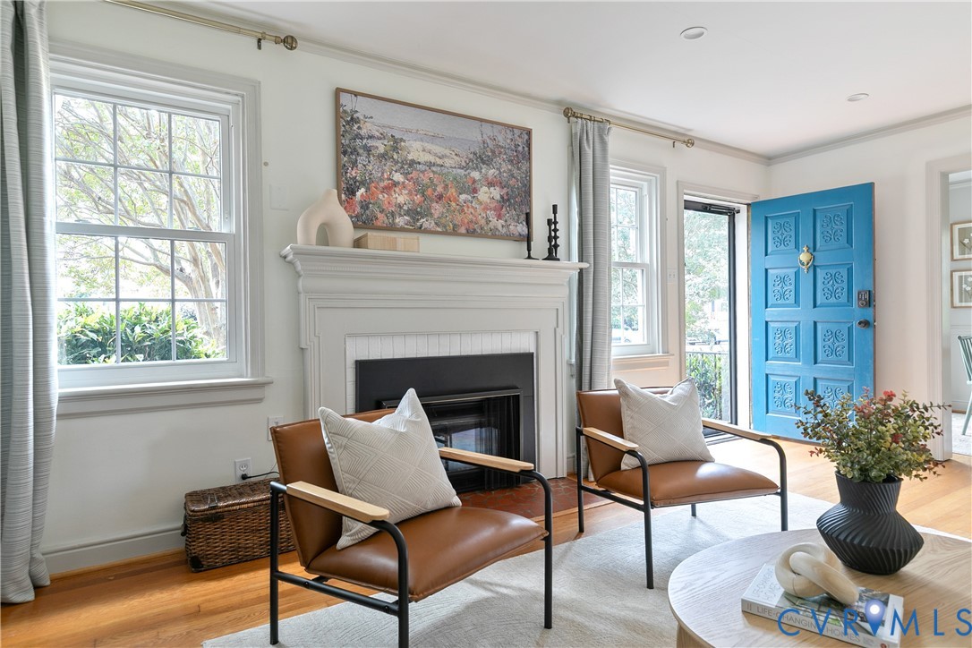 Interior featuring a fireplace with a decorative mantel, wood-finish flooring, multi-pane windows, and a paneled entry door with hardware