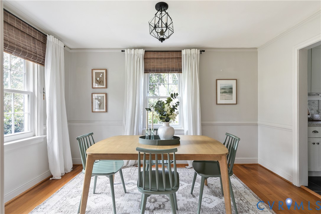 Dining area featuring hardwood flooring, chair rail molding, multi-pane windows, and a geometric pendant light fixture