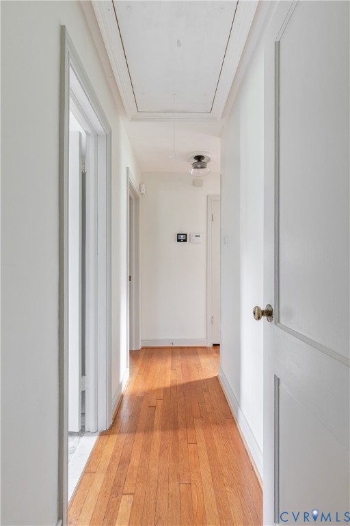 Hallway featuring wood-finish flooring, two-panel interior doors with brass hardware, and flush-mount ceiling lighting