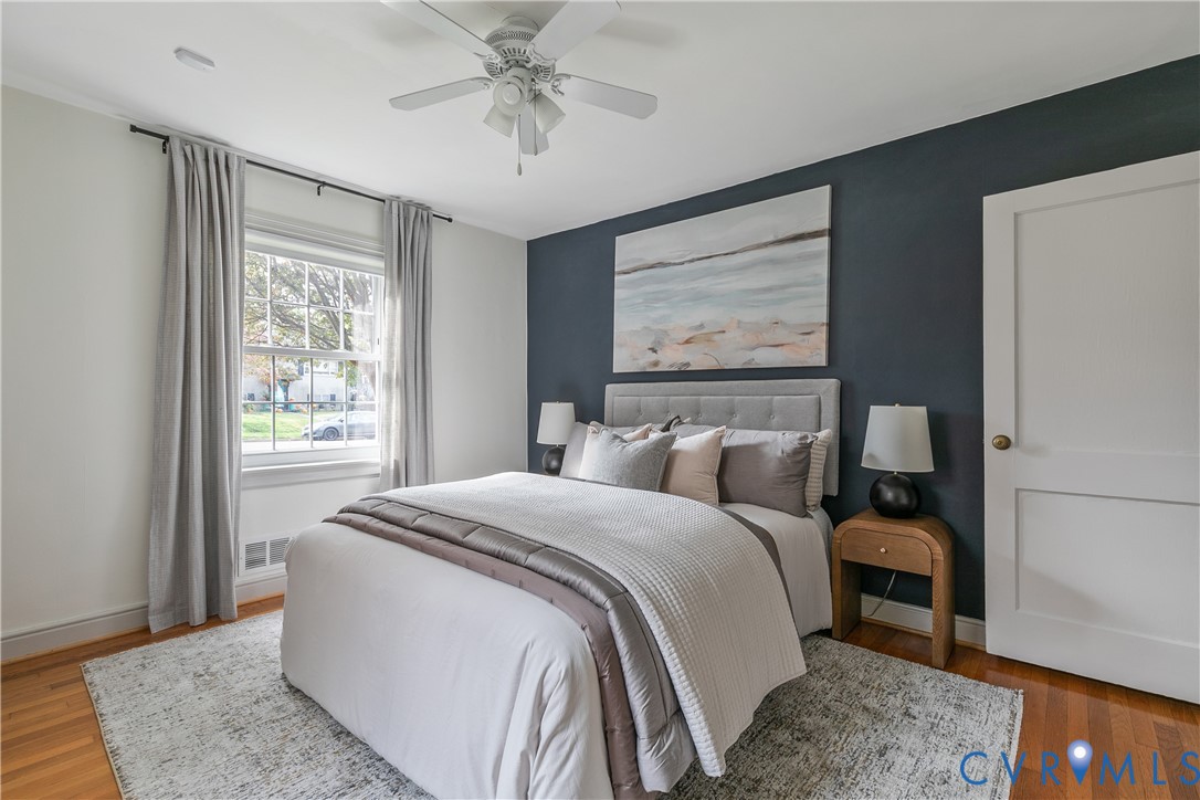 Room featuring wood-finish flooring, a dark accent wall, and a multi-light ceiling fan
