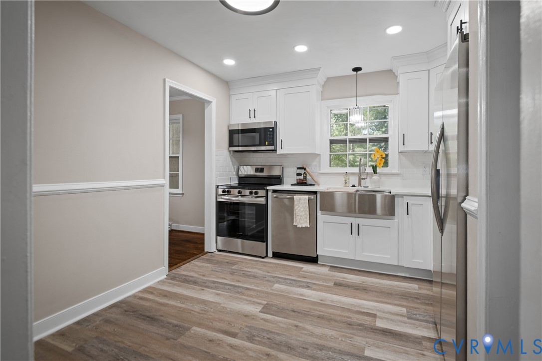 Kitchen featuring white shaker-style cabinetry, stainless steel farmhouse sink, wood-finish flooring, recessed lighting, and a subway tile backsplash