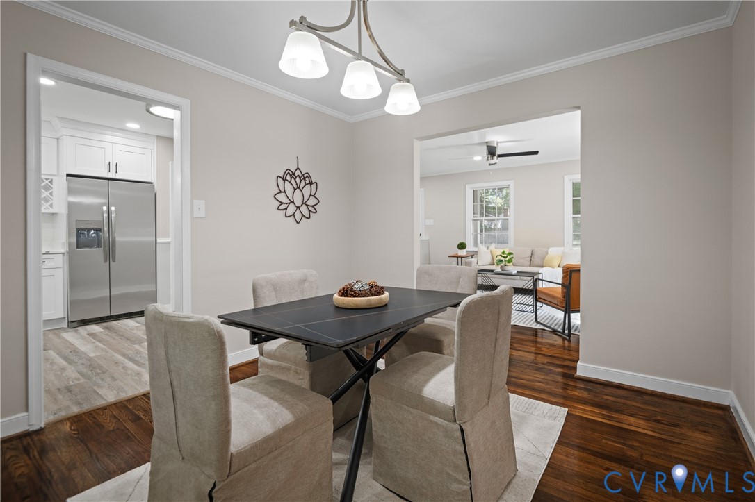 Dining area featuring crown molding, dark wood-finish flooring, and a three-light brushed metal chandelier