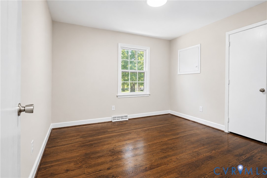 Room featuring wood-finish flooring, neutral wall paint, and a single-hung window with a multi-pane upper sash
