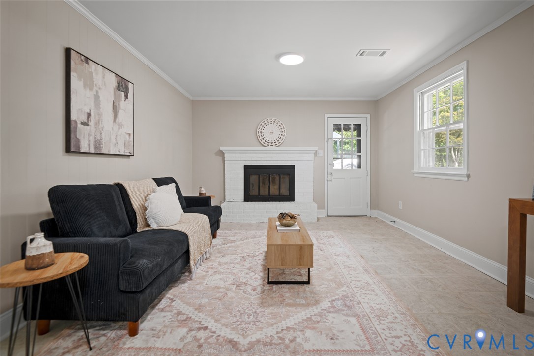 White painted brick fireplace, multi-pane glass entry door, neutral wall color, and multi-pane window