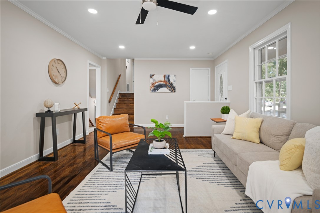 Interior space featuring dark wood-finish flooring, neutral wall paint, recessed lighting, a modern ceiling fan, and a staircase with a wooden handrail