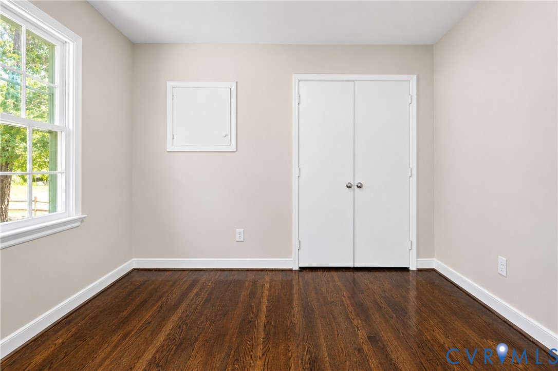 Room featuring wood-finish flooring, a double-door closet, and a multi-pane window with a white frame