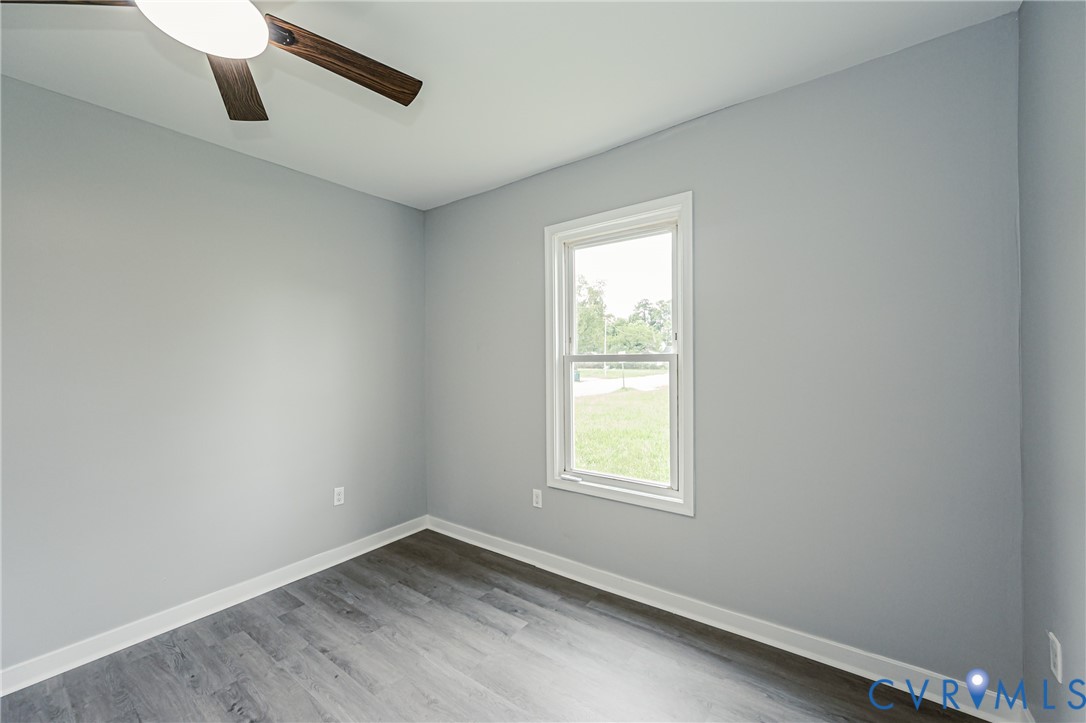 Room featuring wood-finish flooring, neutral wall paint, and a ceiling fan with integrated lighting