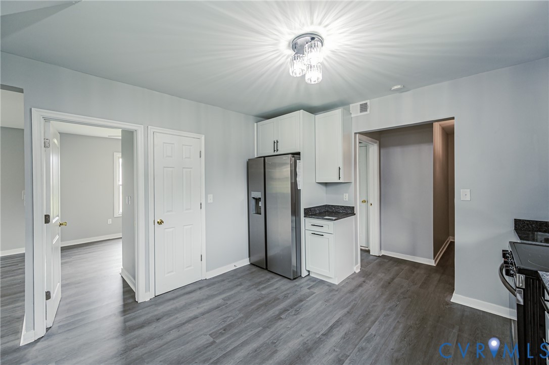 Kitchen featuring wood-finish flooring, white cabinetry with dark hardware, stone-surface countertops, and stainless steel side-by-side refrigerator