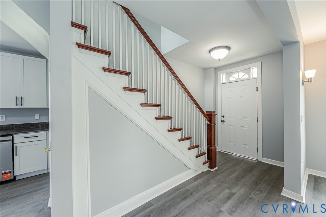 Staircase featuring wood treads and a white balustrade, wood-finish flooring, white panel door with transom window, and flush-mount ceiling lighting