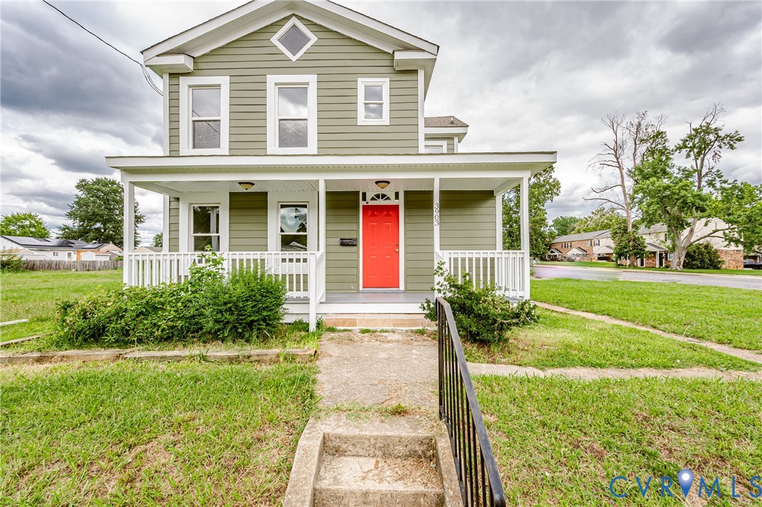 Two-story residence featuring horizontal siding, a covered front porch with white railing, a distinctive diamond-shaped accent window, and a prominent red front door