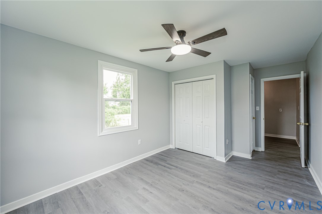 Room featuring wood-finish flooring, a double-panel closet with white doors, a ceiling fan with integrated lighting, and a single-hung window