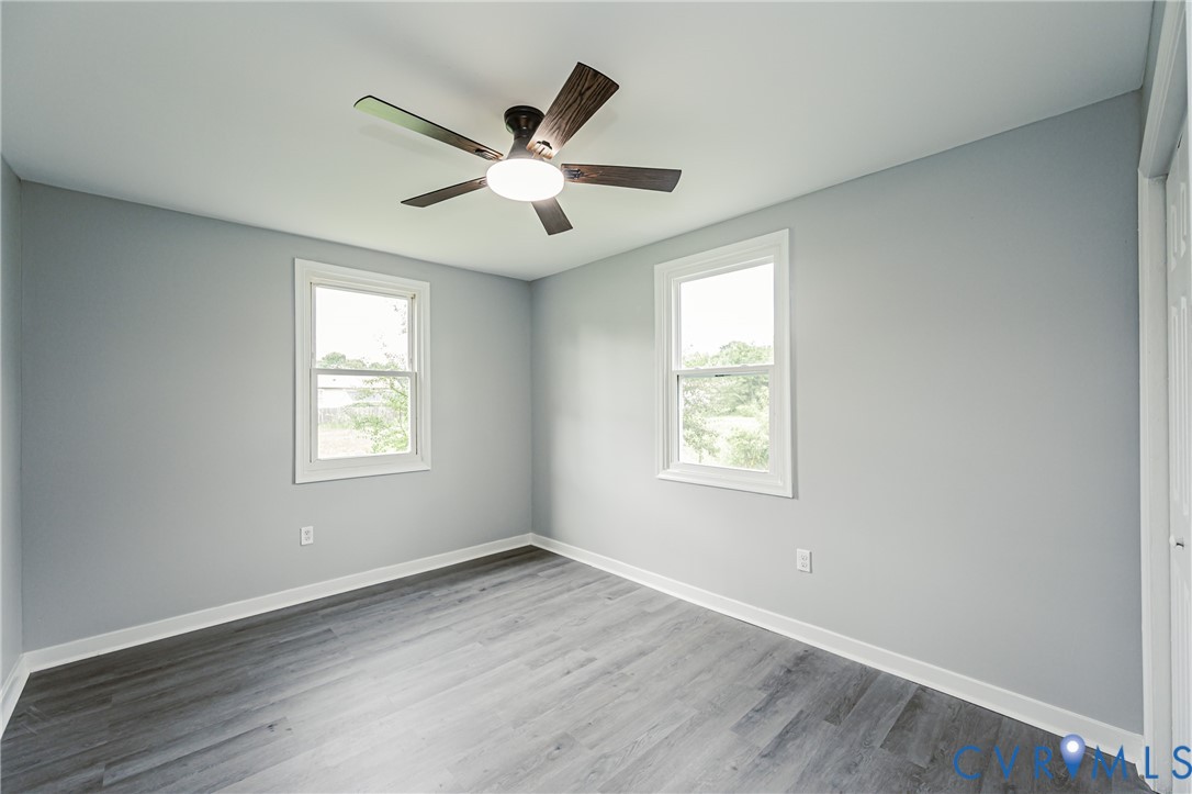 Neutral-toned walls, wood-finish flooring, two single-hung windows, and a central ceiling fan with integrated lighting