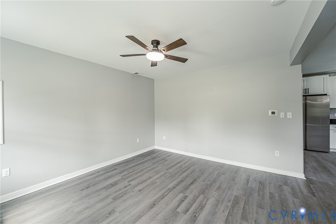 Open interior space featuring wood-finish flooring, neutral wall paint, and a ceiling-mounted fan with integrated light fixture