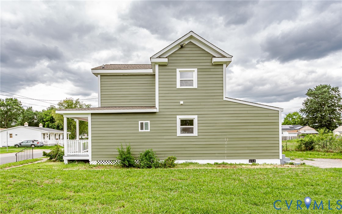 Two-story exterior featuring sage green horizontal siding, white trim, a covered porch with white railing, and a gabled roofline