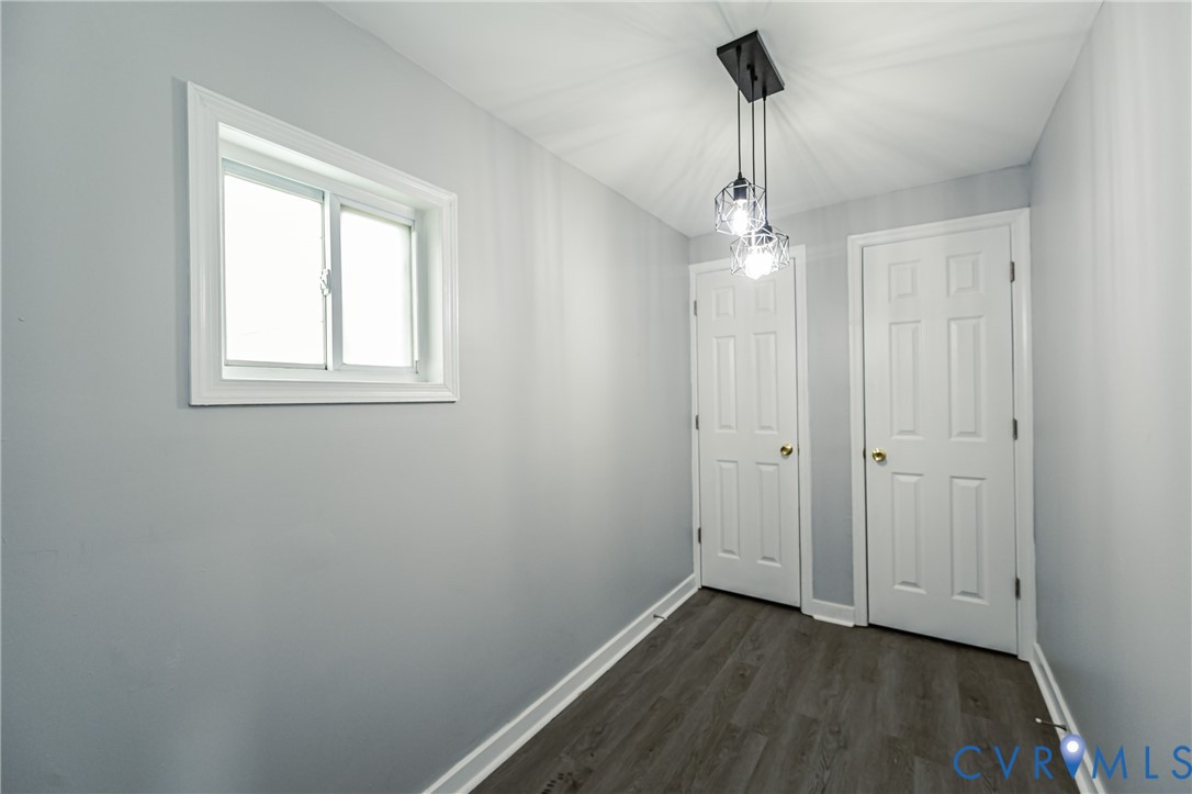 Interior space featuring wood-finish flooring, two six-panel doors, a sliding window, and a multi-pendant geometric light fixture