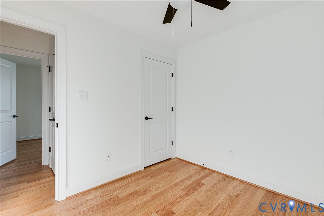 Wood-finish flooring, two-panel interior doors with matte black hardware, and a ceiling-mounted fan with integrated lighting