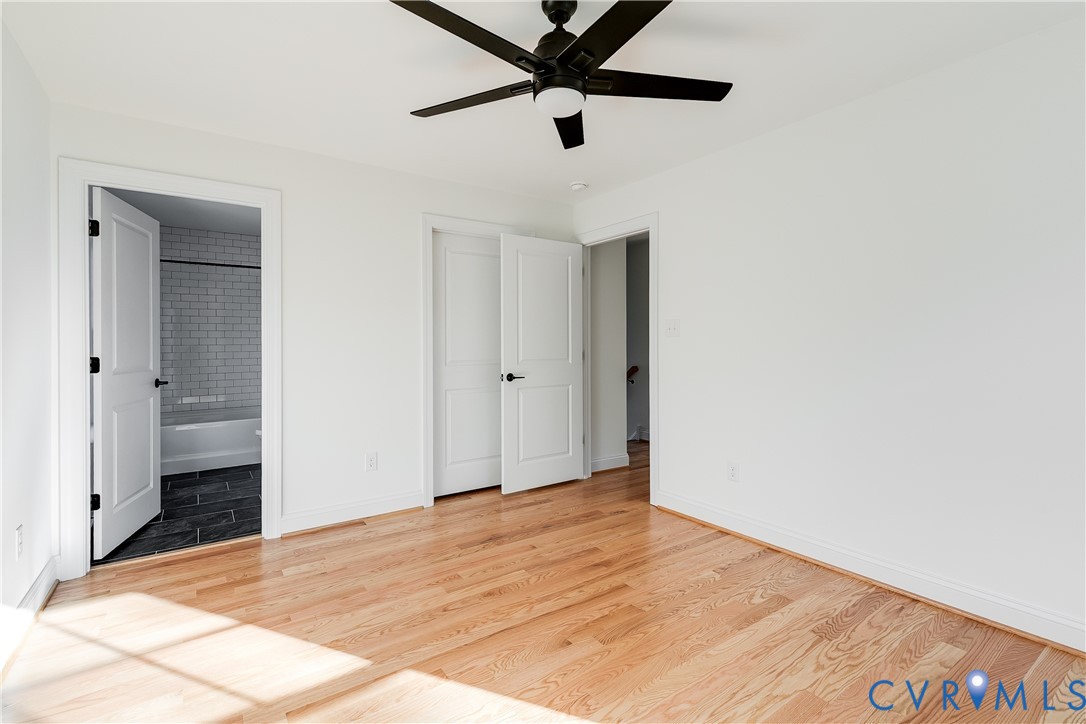 Interior space featuring wood-finish flooring, a matte black ceiling fan with integrated lighting, and multi-panel interior doors with matte black hardware