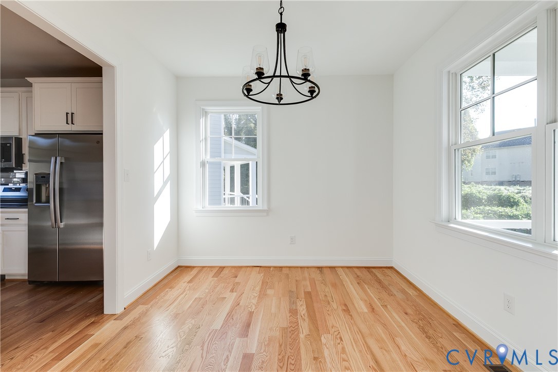Dining area featuring wood-finish flooring, multi-pane windows, and a black-finish metal chandelier