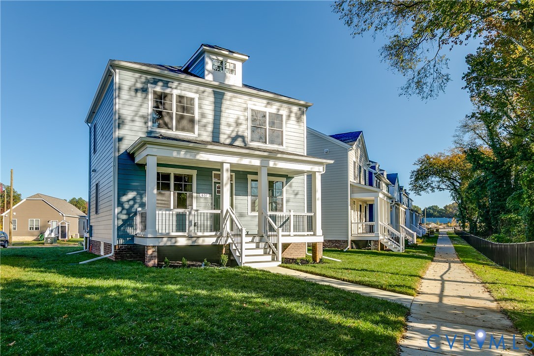 Two-story residence featuring lap siding, a front porch with square columns and balustrades, a dormer window, and a brick foundation Two-story residence featuring lap siding, a front porch with square columns and balustrades, a dormer window, and a brick foundation