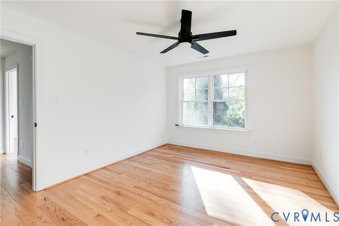 Interior space featuring wood-finish flooring, a multi-pane window, and a matte black ceiling fan